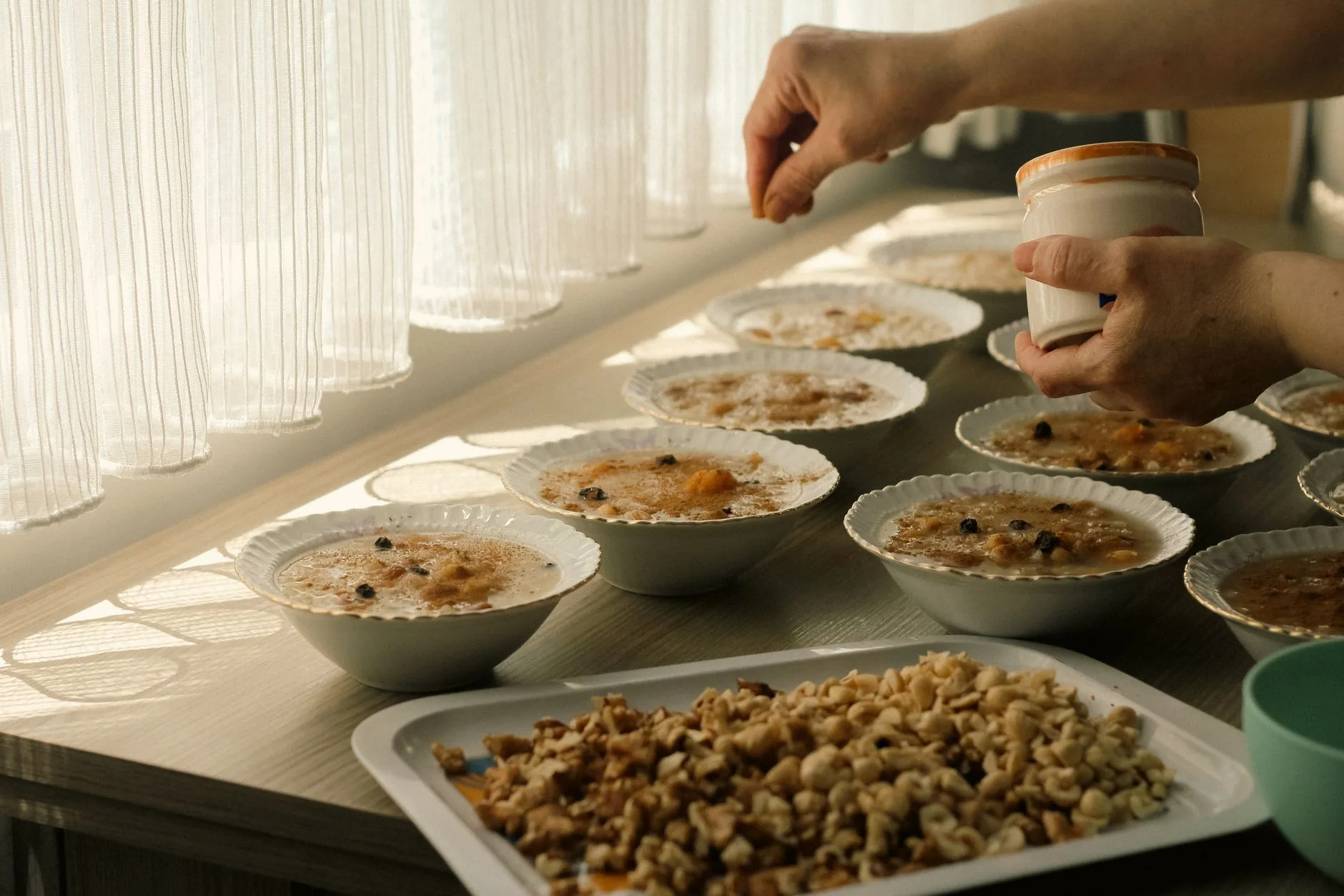 Sunlit kitchen countertop with a bowl of Bircher muesli, fresh fruits, and nuts.