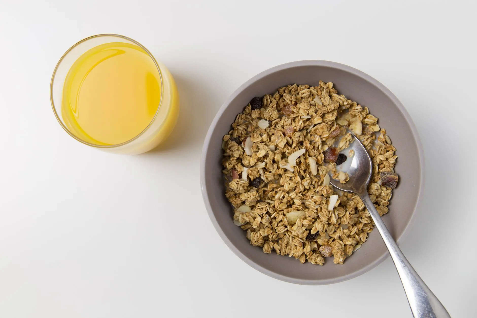 Bircher muesli in a glass bowl on a café table with a spoon.